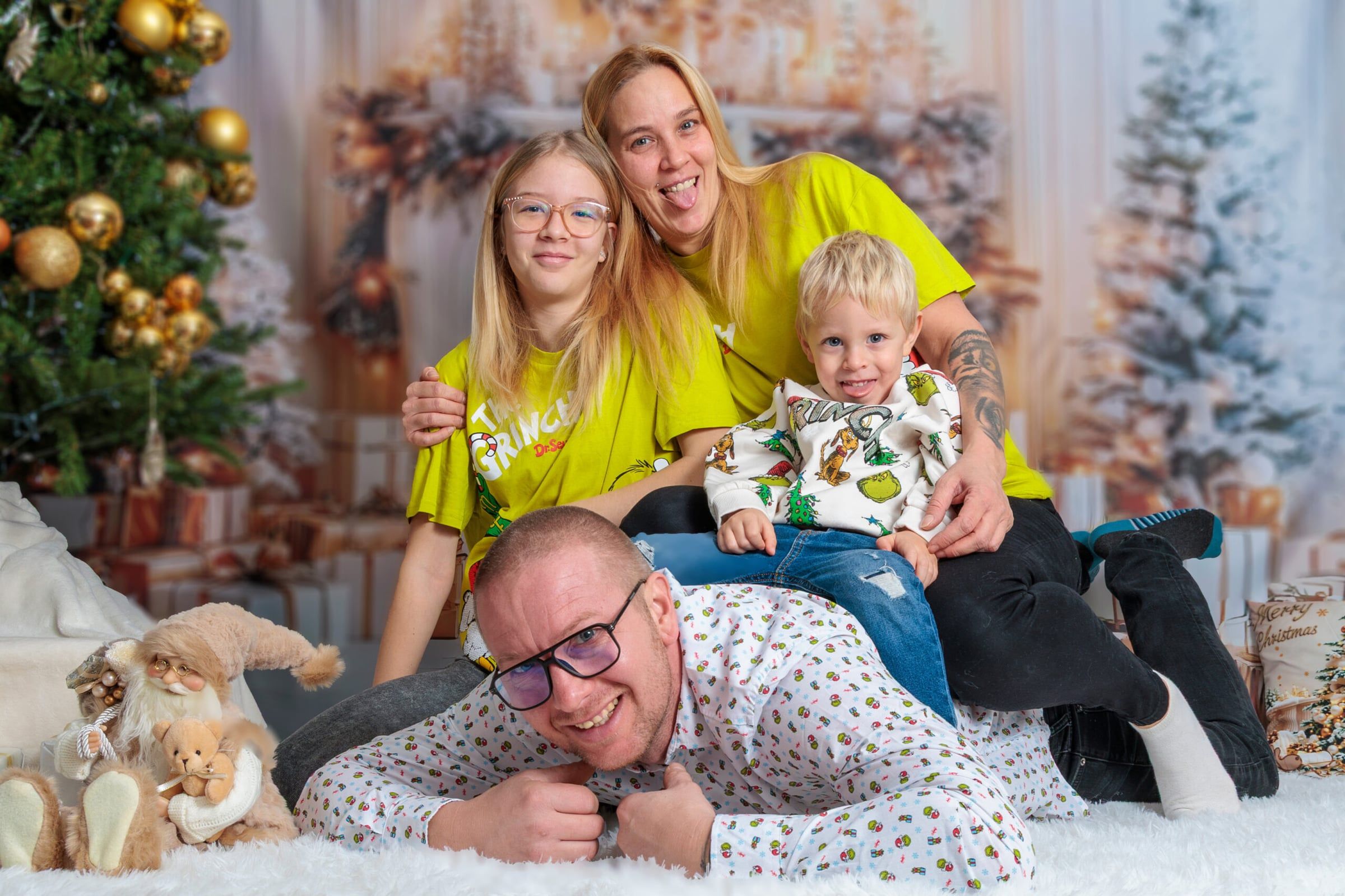 Vidám család a földön fekve, karácsonyfák előtt